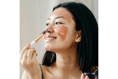 Asian woman applies skin care mask