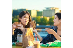 Two young women eating hamburgers and fast food.