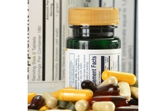 Image Supplement bottle with supplements in front of it and a label in the background.