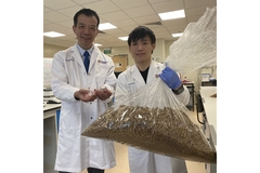 Image Two scientists in the lab in white coats with one holding a bag of grains.