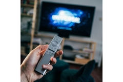 Person pointing remote control at tv.