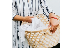 Image A woman holding a laundry basket with a white shirt in it.