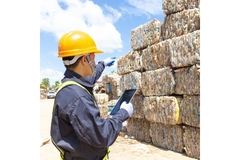 employee at a recycling plant pointing to plastic bales collected for recycling