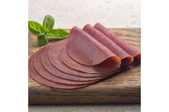 Image Plant-based salami slices on a wooden board.