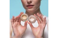 Woman holding up two glass cosmetic jars