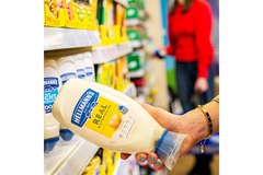 Image Hand holding Hellmann’s mayonnaise in supermarket.