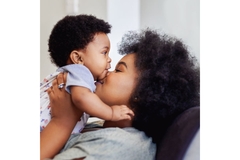 Image Woman holding a baby, kissing it on the cheek.