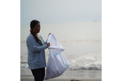 Image woman collecting plastic in a coastal area