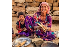Image An Indian woman making atta chapattis with her daughter in frame