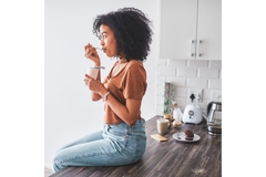 Image Woman sitting on the kitchen counter eating yogurt.