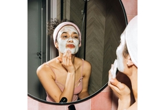 A woman looking in the mirror with a face mask on.