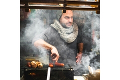 Image Man on market smoking sausages.