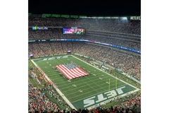 Image MetLife stadium with the NY Jets footbal field at night with a US falg in the middle..