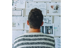Image Researcher looking at a wall with papers and graphs.