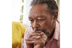 A depressed man wanting to use psilocybin, with his hands under his chin.