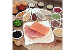Image Sliced fish, nuts, protein powders, lentils, peas and eggs in white bowls kept on a wooden table.
