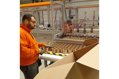 Image Man working with cardboard on machine.