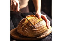 Image A hand cutting sourdough bread with a knife.