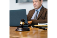 Person sitting behind a computer with a gaffel on the table.
