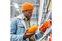 African man looks at packaging of two juice bottles to make a selection