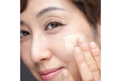 Image An Asian woman putting foundation on her cheek.