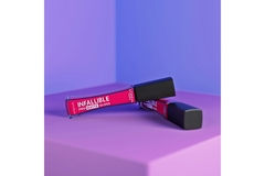 Image Infallible lip gloss on a podium with pink and purple lighting.