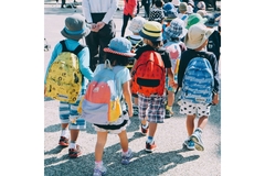 Image Japanese children walking to school wearing backpacks and hats in the sun.
