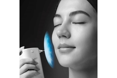 Image A woman using a device on her skin while smiling.