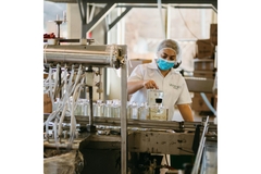 Image woman worker in a glass factory inspects a bottle on packaging line
