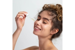 Woman applies serum to cheek with dropper