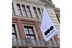 Image dsm-firmenich's flag with logo hanging outside a building.