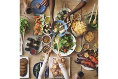 Image Hands on a table with different dishes on a wooden table.