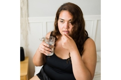 Image Teenage girl taking a GLP-1 medication with a glass of water.