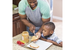 Image Parent making his child a peanut butter sandwich.