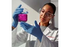 Image A Johnson & Johnson worker holding a beaker filled with pink liquid.