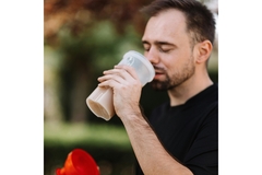 Image A man in a black tshirt drinking a protein shake.