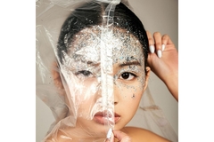 Image Woman wearing glitter makeup covers half her face with plastic