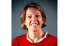 Image A woman in a red sweater smiling.