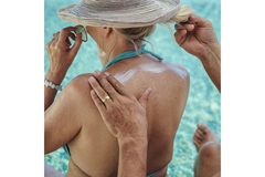 Image man applies sun screen to woman's shoulder by pool