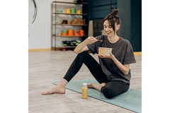 Image Woman eating functional food while sitting on a yoga mat.