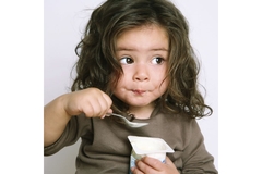 Image Child eating a yogurt from a container.