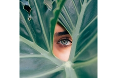 A woman's eye peeking out from the hole of a plant.