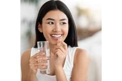 Image A woman takes an omega-3 supplement with water.