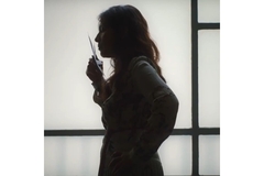 Image A woman smelling a piece of paper.