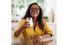 Image Happy woman drinking a glass of milk with postbiotics.