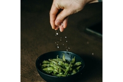 Image Hand sprinkling salt on green beans.