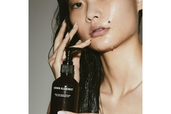 Image A woman with water on her face holding a Grown Alchemist product.