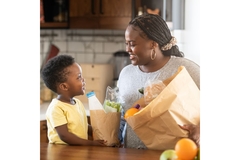 Mother and child putting away groceries in their kitchen.