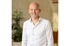 Image A bald man in a white shirt.