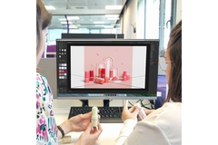 Image Two women sitting at a computer while deisgning packaging which is on the screen.